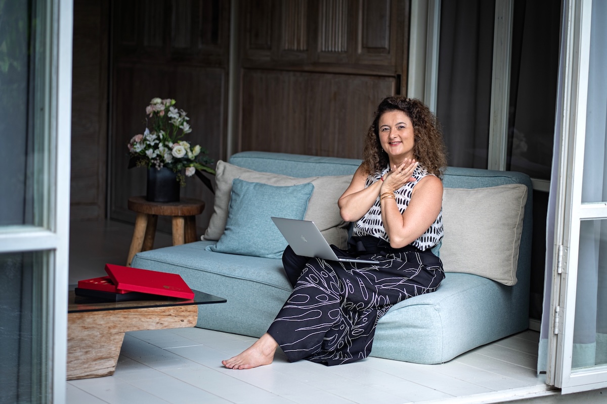 Woman reflecting quietly on a sofa with a laptop