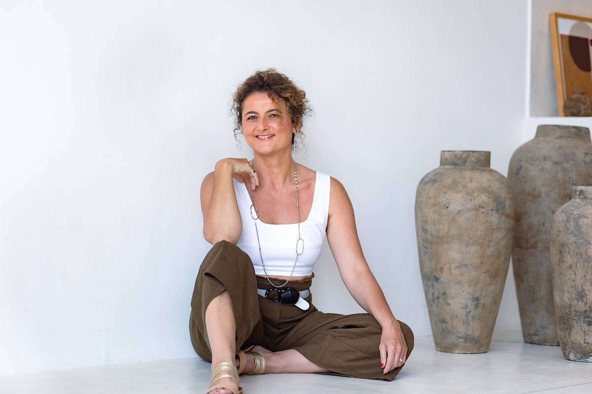 Dijan seated on the floor beside stone vessels