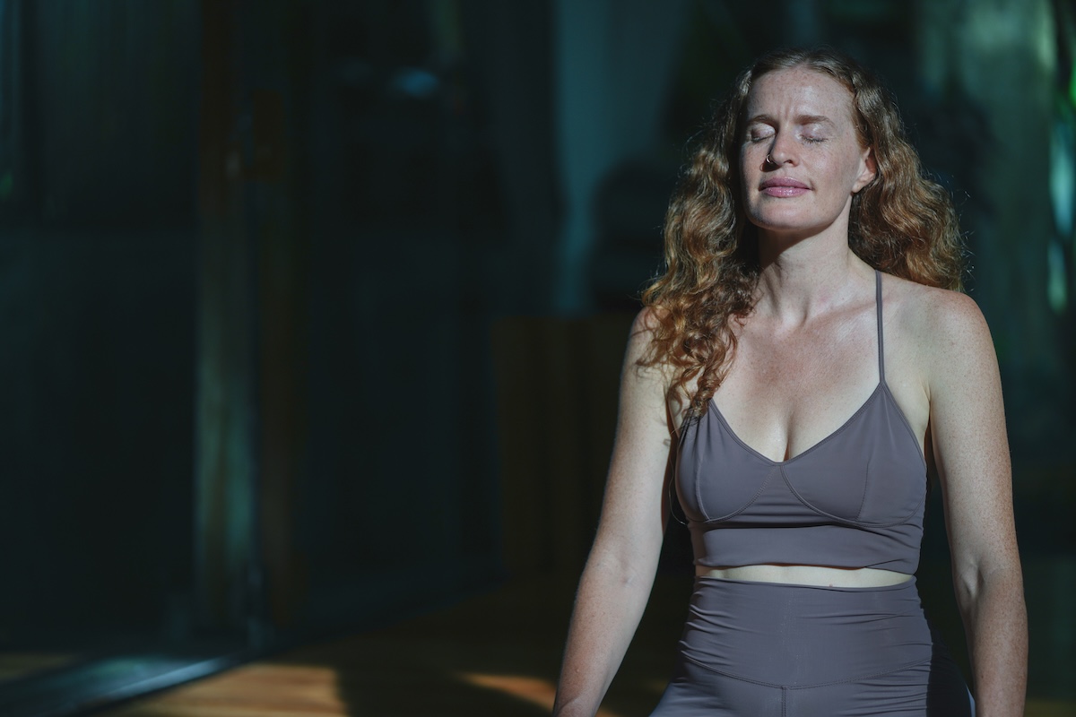 Woman seated with eyes closed in soft directional light during meditation.