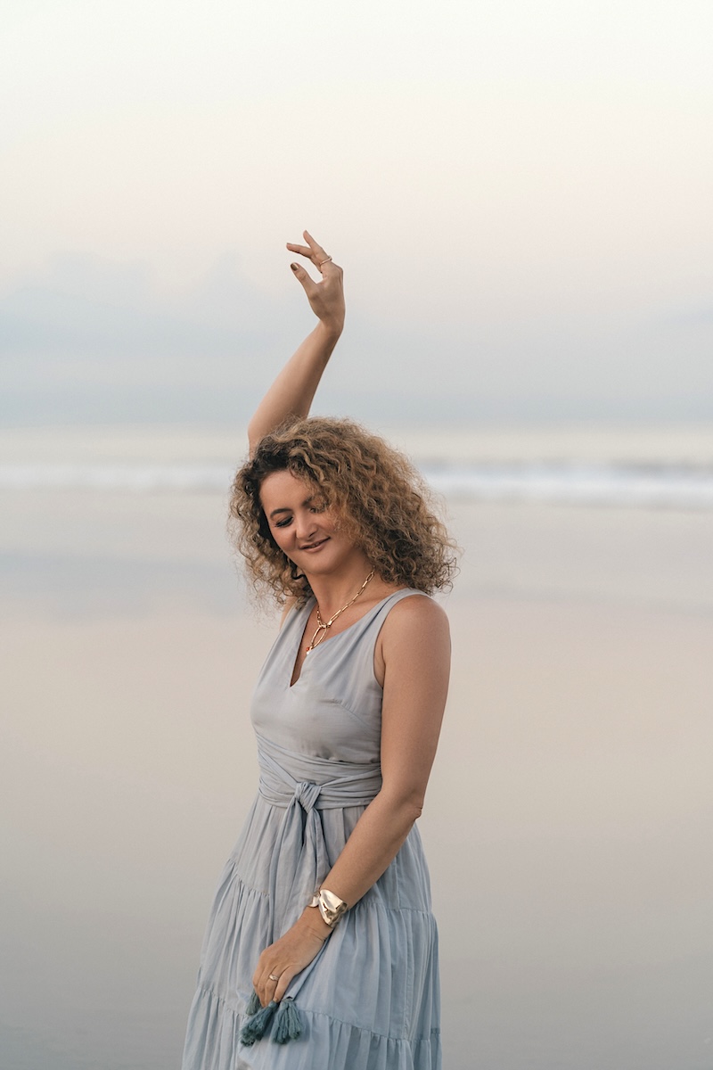 Dijan on a beach at dusk, arm raised gracefully