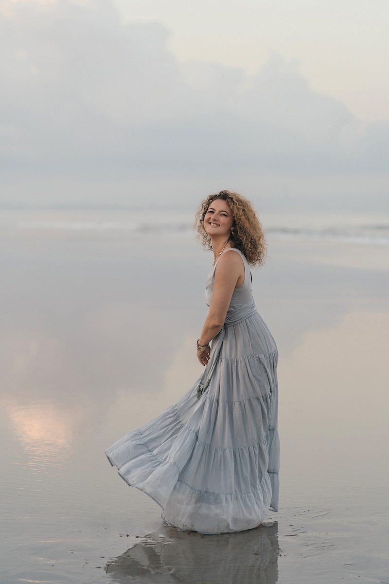 Dijan twirling on wet sand at dusk, smiling
