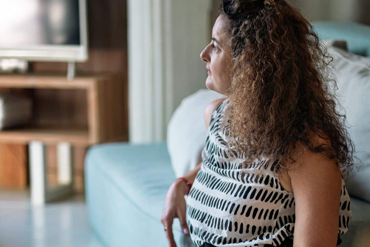 Woman gazing out a window, contemplative, in a living room